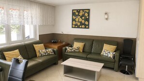 A living room with two green sofas, a coffee table, a side table with a radio, and a painting on the wall. - Majesta Leukerbad # 6-bed apartment, Dusche oder Bad, WC by Interhome (Leukerbad)