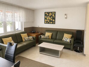 A living room with two green sofas, a coffee table, a side table with a radio, and a painting on the wall. - Majesta Leukerbad # 6-bed apartment, Dusche oder Bad, WC by Interhome (Leukerbad)