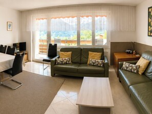 Ein Wohnzimmer mit einem grünen Sofa, einem Couchtisch und einem Essbereich mit Stühlen und einem Tisch.