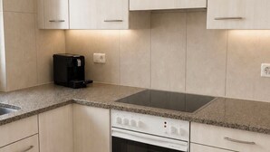 A modern kitchen with light-colored cabinets, a built-in oven, and a countertop with a coffee maker. - Majesta Leukerbad # 6-bed apartment, Dusche oder Bad, WC by Interhome (Leukerbad)