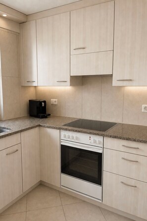 A modern kitchen with light-colored cabinets, a built-in oven, and a countertop with a coffee maker. - Majesta Leukerbad # 6-bed apartment, Dusche oder Bad, WC by Interhome (Leukerbad)