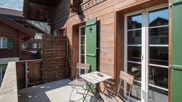 Un edificio in legno con un balcone, un tavolo e due sedie.