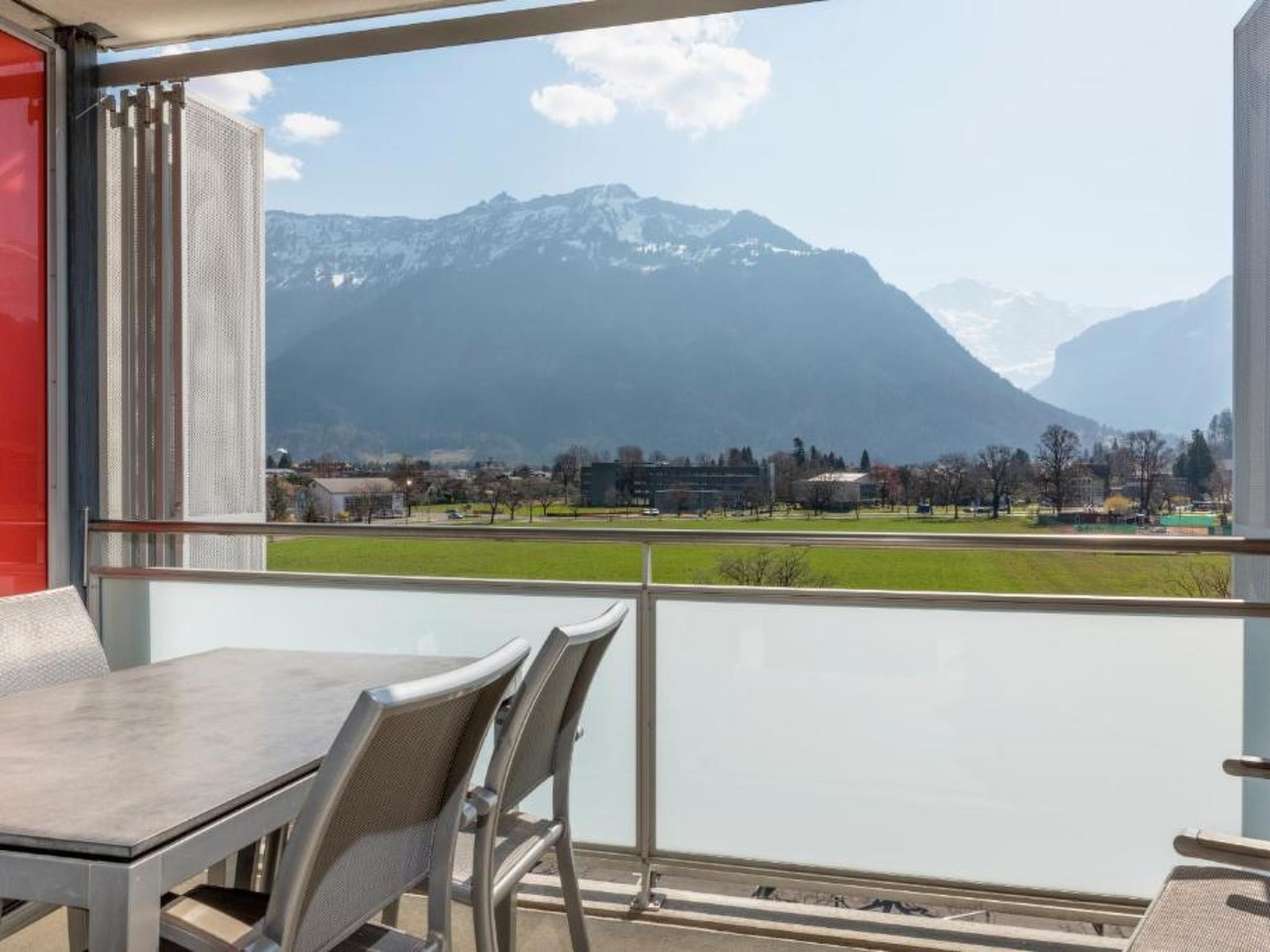 Un balcon avec vue sur une chaîne de montagnes et un terrain de sport.