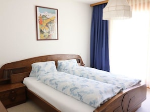 Ein Doppelbett mit floralem Bettbezug, einem Holz-Kopfteil und Nachttischen.