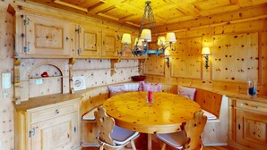 A wooden interior with a round dining table, chairs, and a chandelier.