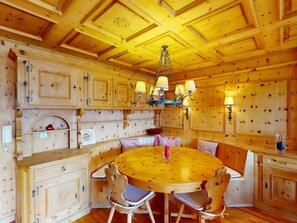 A wooden interior with a round dining table, chairs, and a chandelier. - Apartment Tinus by Interhome (St. Moritz)
