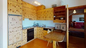 A compact kitchen with wooden cabinetry, a built-in oven, and a dining area with a bench.
