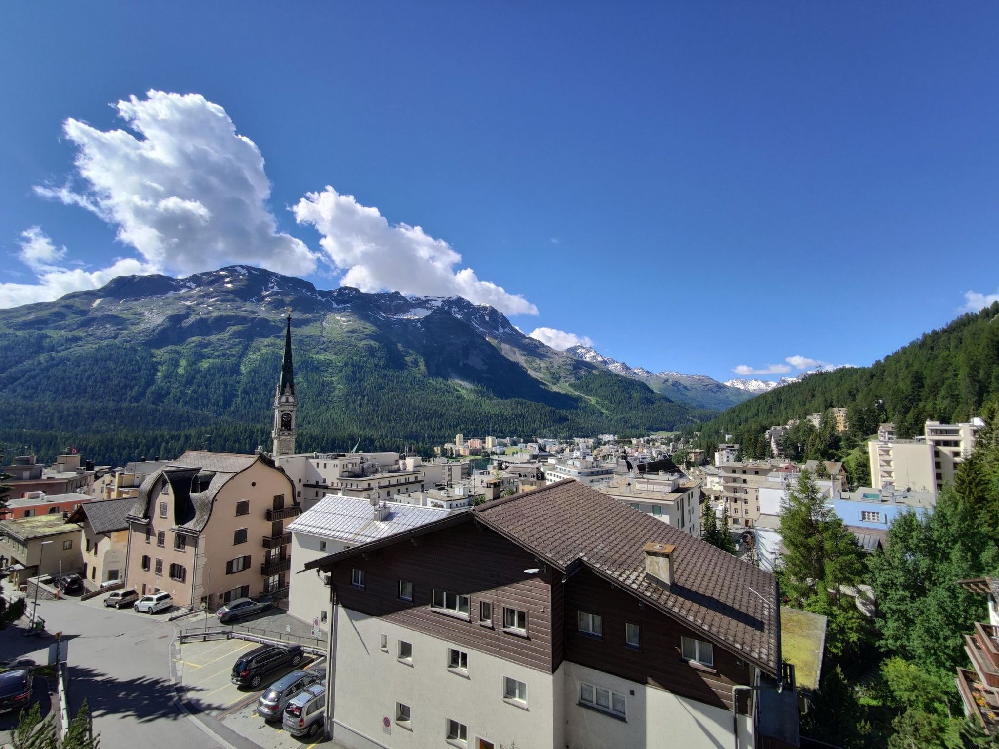 A town with a prominent church, residential buildings, and a mountain backdrop.