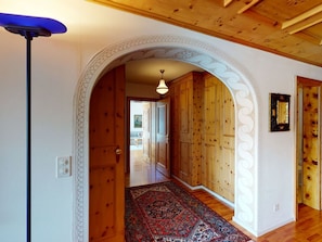 A hallway with wooden walls, a patterned rug, and a ceiling fan. - Apartment Tinus by Interhome (St. Moritz)