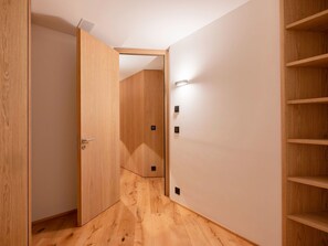 A hallway with wooden flooring, a door, and a wall-mounted shelf unit. - Apartment Mira Lej by Interhome (St. Moritz)