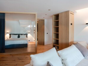 A modern bedroom with a bed, bedside lamps, a wooden wardrobe, and a view through a glass door. - Apartment Mira Lej by Interhome (St. Moritz)
