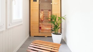 Un sauna avec une porte en bois, un banc et une plante en pot.