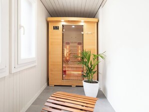 Ein Saunaraum mit Holztür, einer Sitzbank und einem Blumentopf.