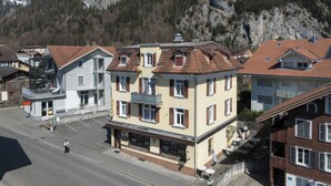 Un immeuble à plusieurs étages, de style architectural européen traditionnel, doté d’une cour intérieure avec des espaces de détente en plein air, et entouré d’immeubles d’habitation.