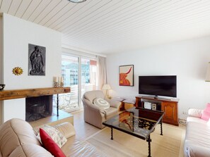 A living room with a fireplace, a television, and a sofa. - Apartment Skyline 307 by Interhome (St. Moritz)