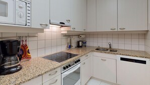 Eine Küche mit weißen Schränken, einer Granitabdeckung, einem Backofen, einer Kaffeemaschine und einem Geschirrspüler.