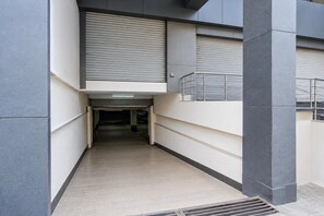 A narrow corridor with a metal grate at the bottom, leading to a door at the end.
