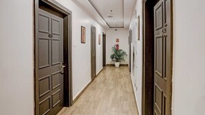 A hallway with doors, a potted plant, and a fire extinguisher.