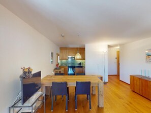 Eine moderne Küche mit Holzschränken, einem Esstisch mit Stühlen und einer Pendelleuchte.