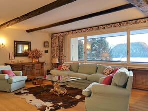 A cozy living room with a sofa, a glass coffee table, and a cowhide rug. - Apartment Muntagna Alva OG by Interhome (St. Moritz)