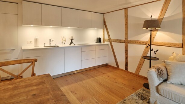Una cocina moderna con armarios blancos, una mesa de comedor de madera y una lámpara de pie.