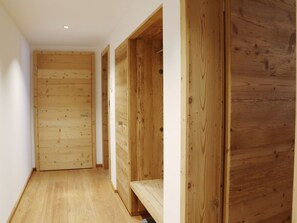 Ein schmaler Gang mit Holzwänden und einer Holztür am Ende.