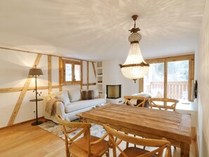 Ein gemütliches Zimmer mit einem Holztisch, Stühlen, einer Couch, einer Stehlampe und einer Pendelleuchte.