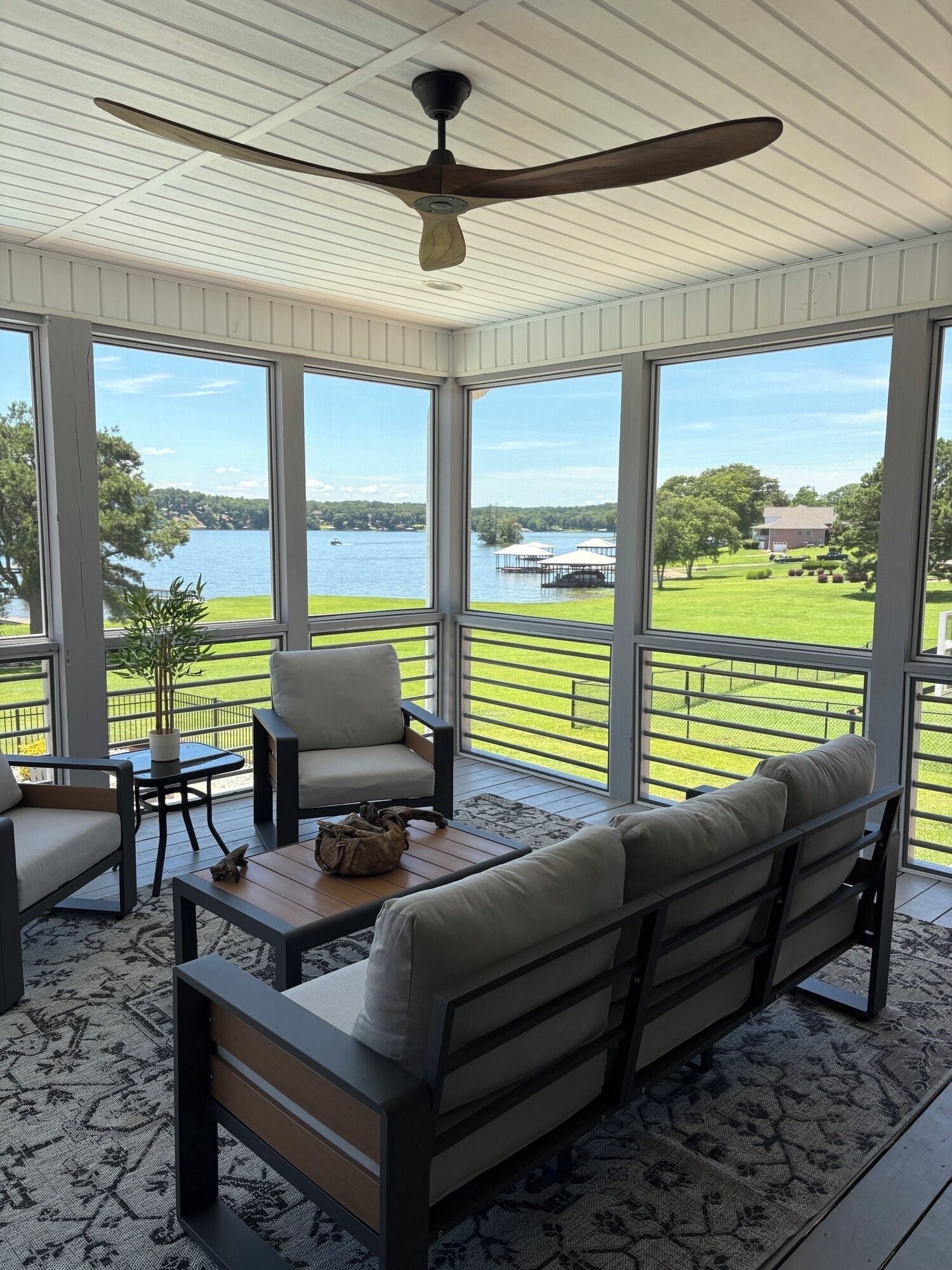 A sunroom with a ceiling fan, large windows, a sofa, a chair, and a coffee table.