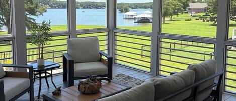 A sunroom with a ceiling fan, large windows, a sofa, a chair, and a coffee table.