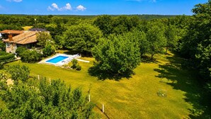A residential property with a swimming pool, surrounded by lush greenery and trees. - A house surrounded by forest. (Valtura)