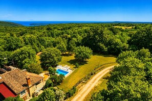 An aerial view of a property with a swimming pool, a dirt path, and dense greenery. - A house surrounded by forest. (Valtura)