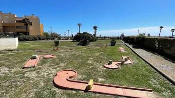A grassy area with a winding path and a building in the background.