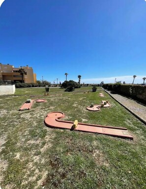 A grassy area with a winding path and a building in the background. - Our rental in Barcarès for 4 people. Pool, AC, beach, and Lydia within walking distance (Le Barcares)