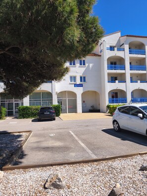 A building with a reception area, multiple balconies, and a parking lot. - Our rental in Barcarès for 4 people. Pool, AC, beach, and Lydia within walking distance (Le Barcares)