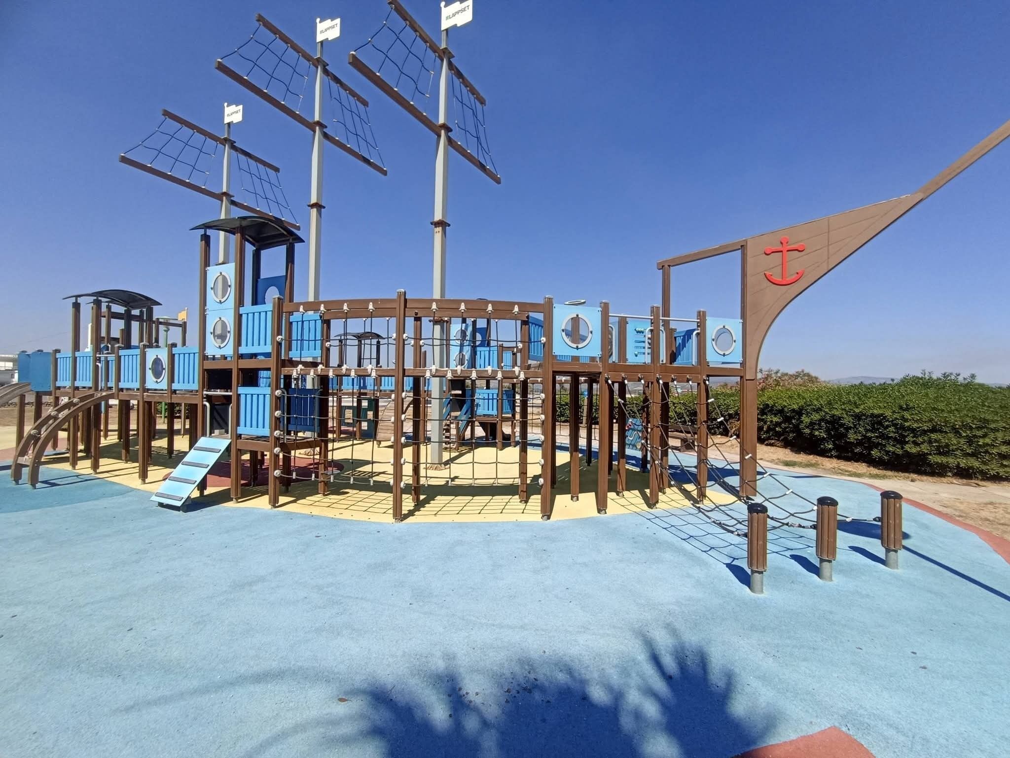 Um parquinho com uma estrutura de recreação temática de navio, incluindo redes de escalada e escorregadores.