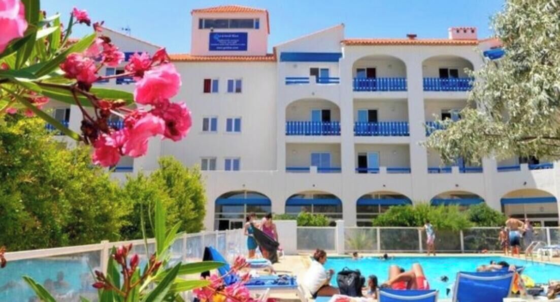 Un hôtel doté d’une piscine, de plusieurs balcons et offrant une vue sur un ciel dégagé.