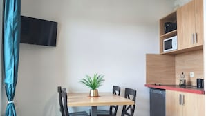 Et kompakt køkken med spisebord, stole, en potteplante, en mikrobølgeovn og en opvaskemaskine.