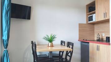 A compact kitchen with a dining table, chairs, a potted plant, a microwave, and a dishwasher.