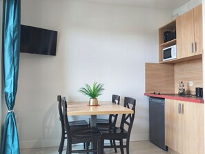 A compact kitchen with a dining table, chairs, a potted plant, a microwave, and a dishwasher. - Our rental in Barcarès for 4 people. Pool, AC, beach, and Lydia within walking distance (Le Barcares)