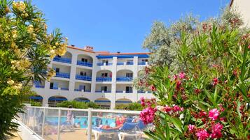 A hotel with a pool area, multiple balconies, and lush greenery.
