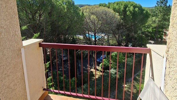 Ein Balkon mit Blick auf Bäume und einen klaren Himmel.