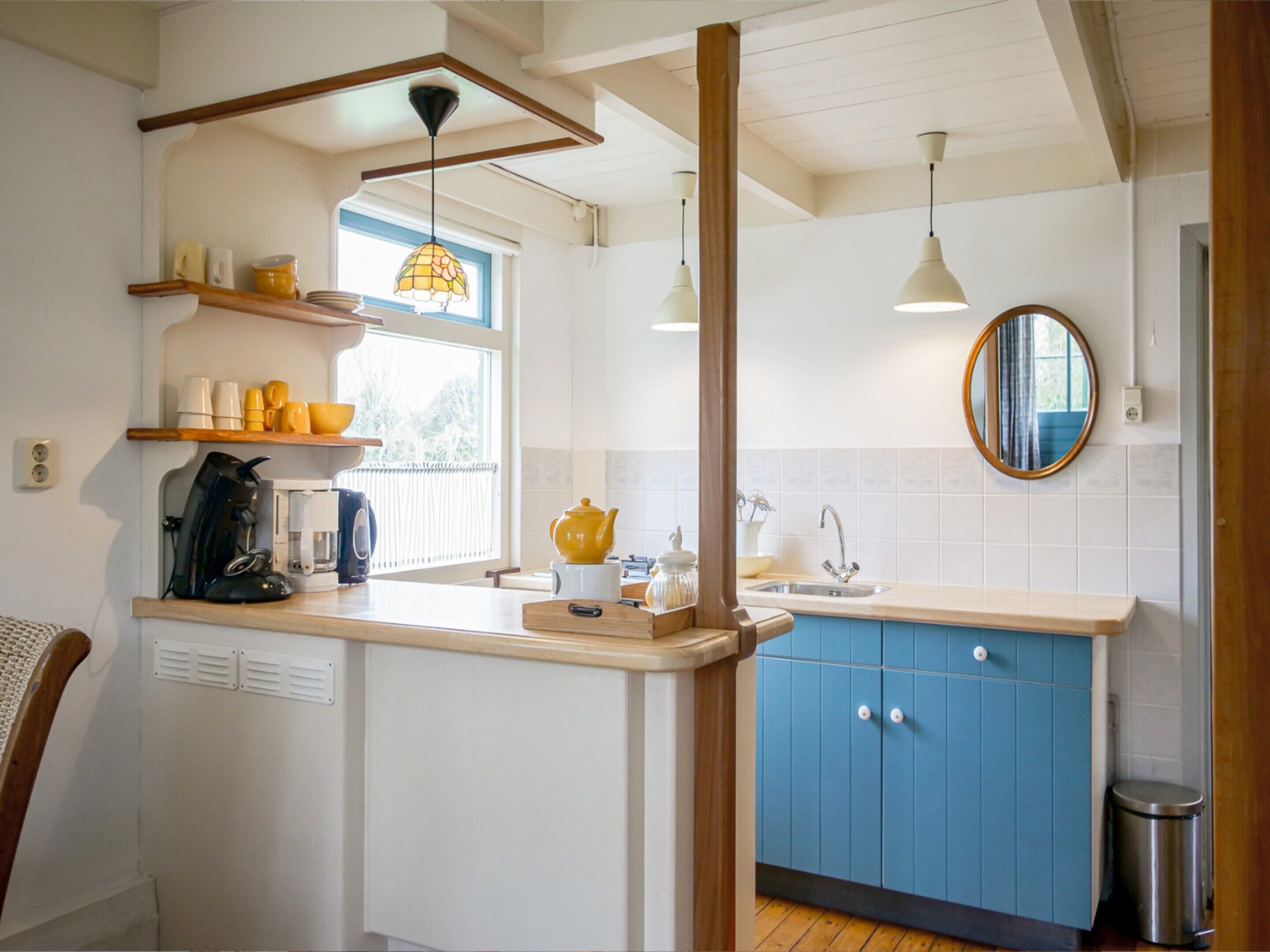 Een keuken met een houten aanrecht, een spoelbak, een raam en een spiegel.