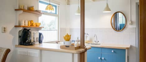 A kitchen with a wooden countertop, a sink, a window, and a mirror.