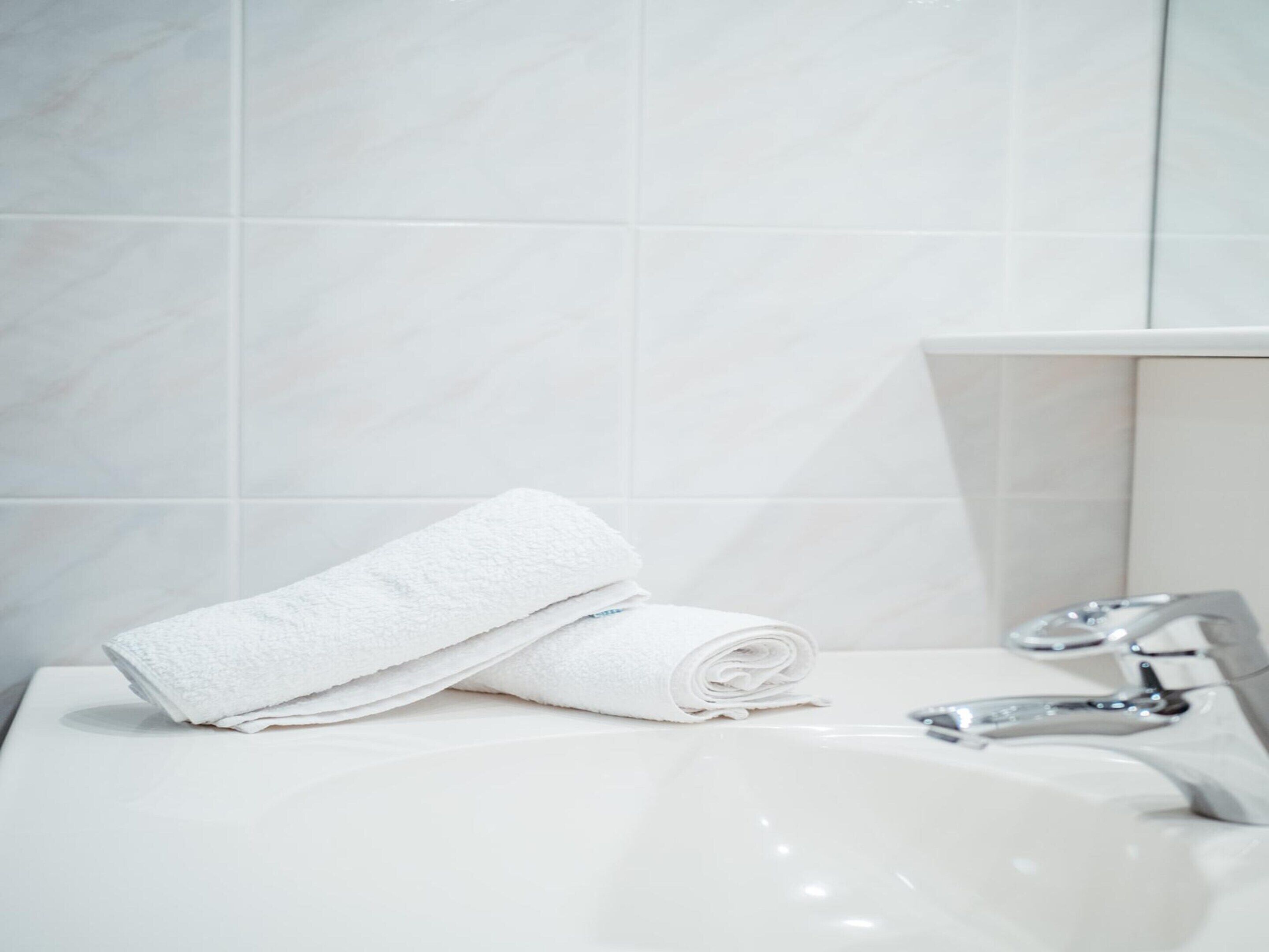 A bathroom with a white sink, a mirror, and a towel.