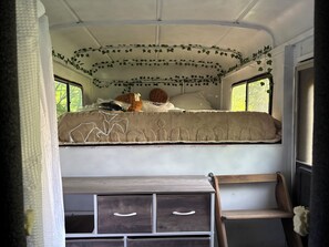 Ein kompakter, übersichtlicher Innenraum mit Etagenbett, kleinem Schreibtisch und Fenster für natürliches Licht.