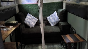 A compact room with a green wall, a sofa with cushions, a small table, and a bench.