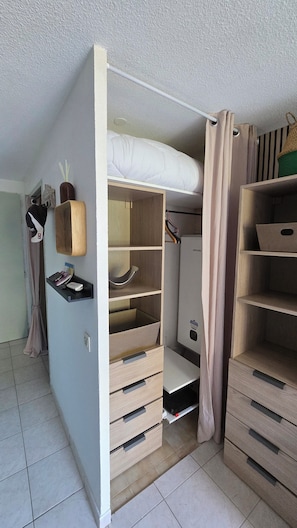 A compact room with a bunk bed, wooden drawers, a shelf with a vase, and a hanging coat rack. - Bormes-les-Mimosas—Quiet 4-bedroom home with AC, Wi-Fi, parking, and a basement, near the heart of La Favière (Bormes-les-Mimosas)