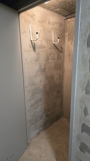 A small, enclosed space with a concrete wall, two white hooks, and a concrete floor. - Bormes-les-Mimosas—Quiet 4-bedroom home with AC, Wi-Fi, parking, and a basement, near the heart of La Favière (Bormes-les-Mimosas)