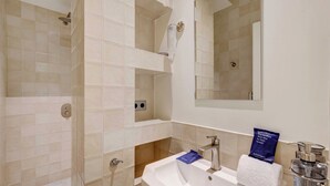 A bathroom with a shower, sink, mirror, and toiletries. - Cozy Appartement a/c 1br/2p- Montmartre (Paris)