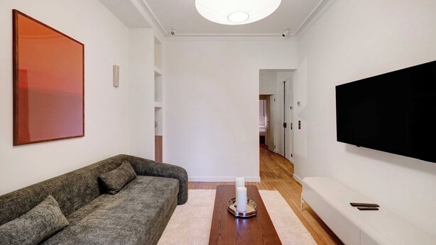 A modern living room with a sofa, a coffee table, and a flat-screen TV mounted on the wall. - Cozy Appartement a/c 1br/2p- Montmartre (Paris)